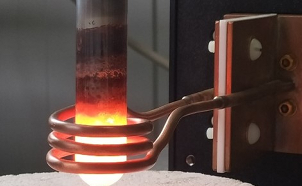 Induktionsspule erhitzt ein Metall in einem Rohr.
